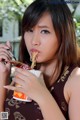 A woman eating a bowl of noodles with a spoon.